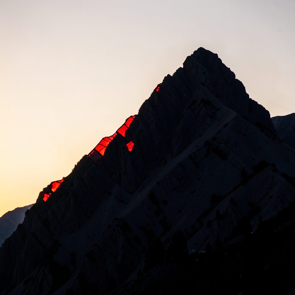 A rugged mountain ridge at golden hour, warm amber and deep slate tones